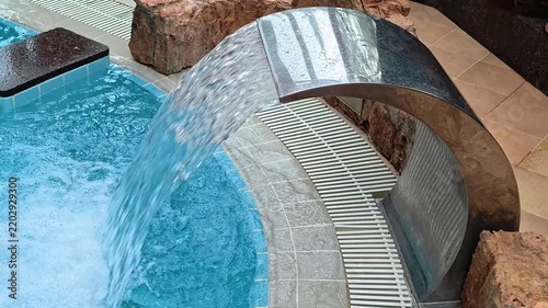 A pool with a natural waterfall flowing out of it, suitable for relaxation and outdoor settings