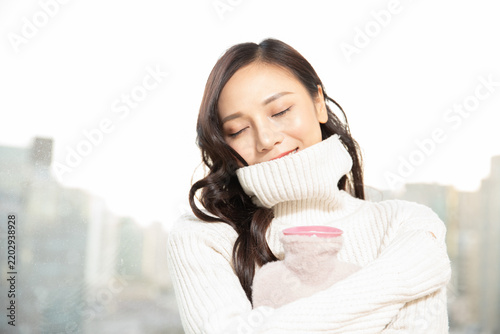 Konstfotografi Cozy Woman in White Sweater Holding Warm Mug by Window