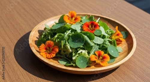 A wooden bowl displays a vibrant salad with orange edible flowers. Natural light and table