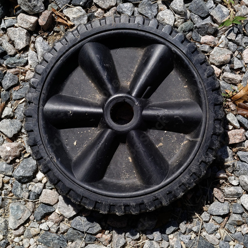 Black Plastic Wheel on Gravel Surface
