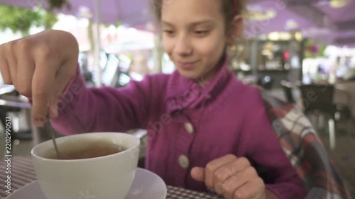 Little beautiful girl in drinking tea in cafe