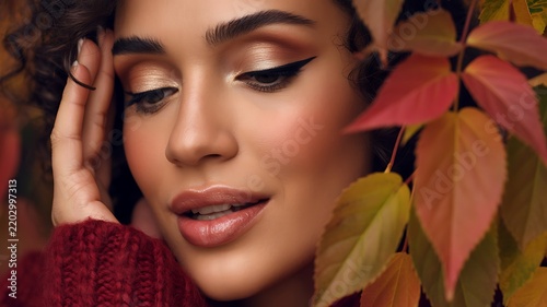 Woman surrounded by autumn leaves in a warm seasonal beauty portrait