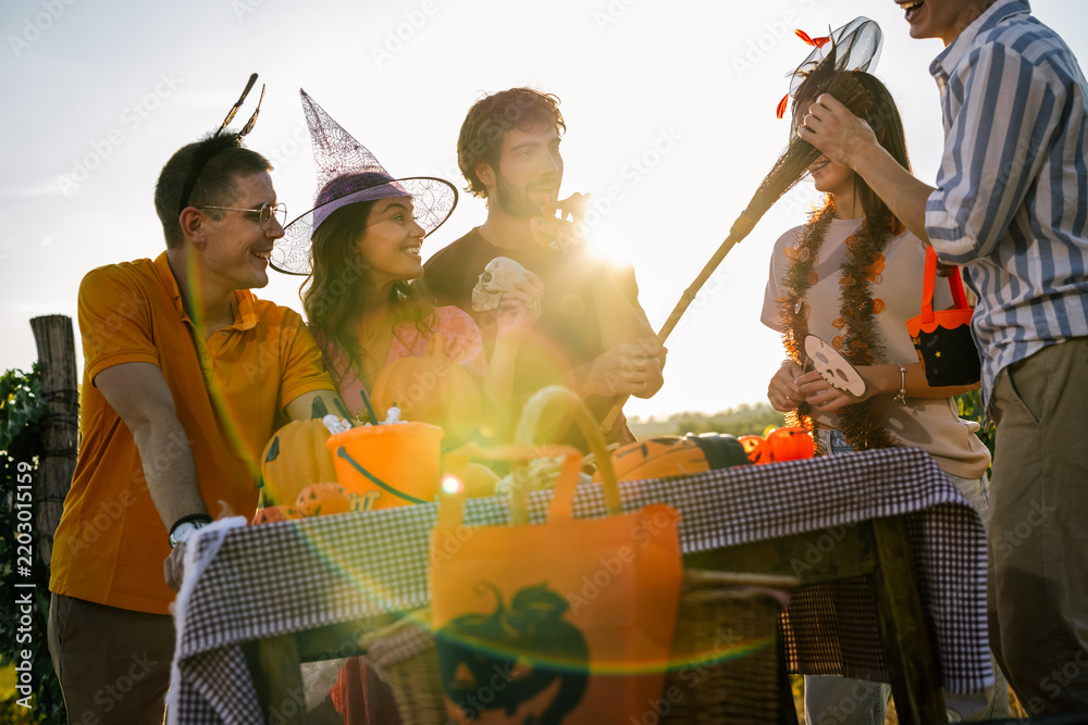 Obraz premium Friends wearing Halloween costumes enjoying sunset light at an outdoor vineyard party.
