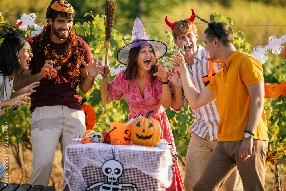 Obraz premium Close up of playful friends in Halloween costumes laughing and having fun at an outdoor party.