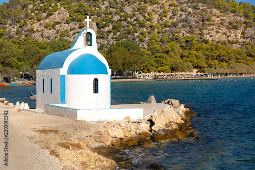 Small white Cycladic-style church beside the water at Vouliagmeni Lake near Loutraki, Greece, photographed in the early morning