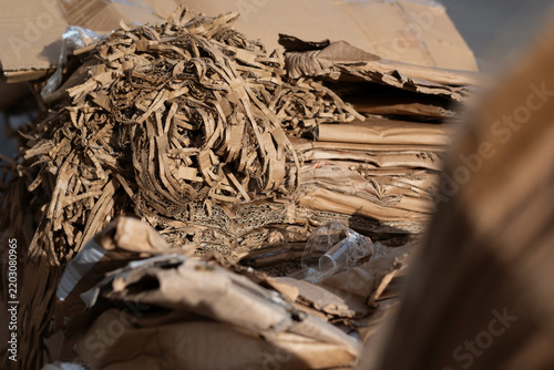 Close-up of pile of shredded corrugated cardboard and flattened boxes, showing layered textures and fibrous edges of recyclable packaging material, reuse or processing in recycling operations