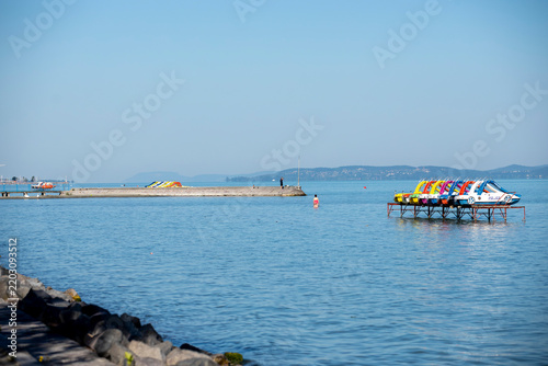 Colorful pedal boats moored at a pier on a calm lake at Lake Balaton