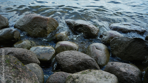 Wet stones in water with ripples, nature background closeup