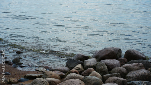 Calm water ripples washing over stones on the shore