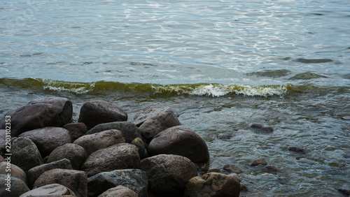 Water waves washing over large stones on the shore