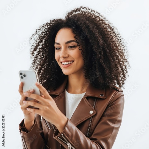 Smiling woman holding smartphone while wearing leather jacket