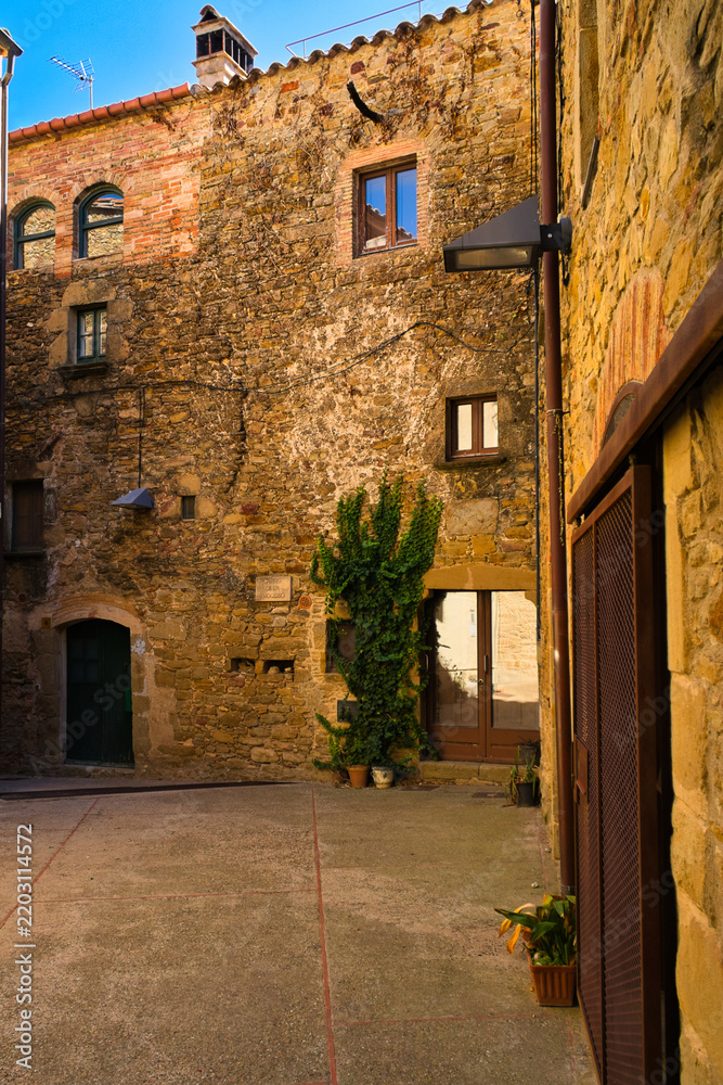Fototapeta premium Rustic stone courtyard with greenery and warm Mediterranean light 