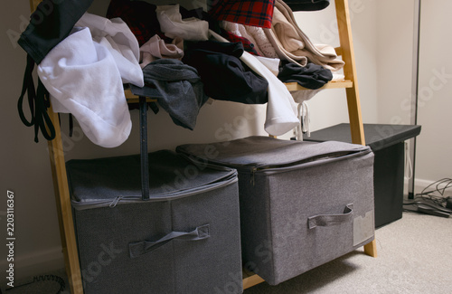 Cluttered clothes on shelf, storage boxes.