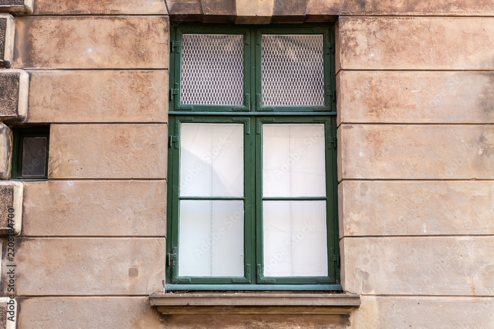 Obraz premium Rectangular wooden window with green frame in rusticated stone wall