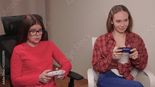 Women play games. Relaxed friends enjoying video games with cheerful interactions. Two women engage in friendly game night amid comfortable surroundings and joyful laughter