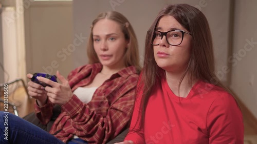 Women play games. Relaxed friends enjoying video games with cheerful interactions. Two women engage in friendly game night amid comfortable surroundings and joyful laughter