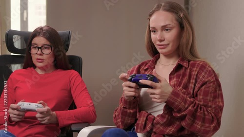 Women play games. Relaxed friends enjoying video games with cheerful interactions. Two women engage in friendly game night amid comfortable surroundings and joyful laughter