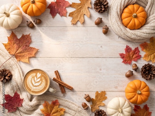 Autumn flat lay with pumpkins, maple leaves, acorns, latte and knitted scarf on white wooden table with copy space
