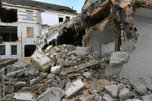 Demolition site showing a partially torn down apartment building wall and exposed structure.