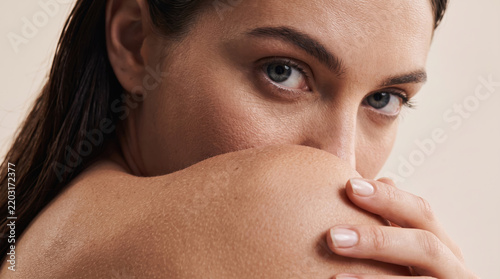 Woman looking over her shoulder with an intense gaze, highlighting natural beauty, clean skin, and wellness concepts suitable for skincare and cosmetic advertising