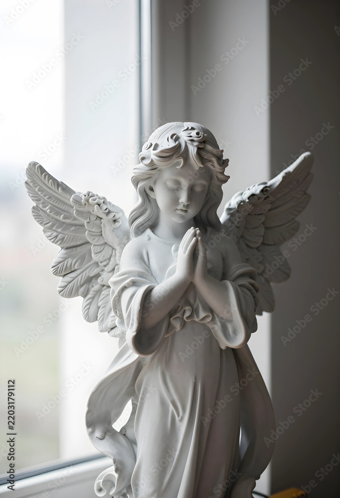 Fototapeta premium Spirituality and faith concept stone angel statue with hands in prayer position for religious peace hope and comfort in a quiet indoor setting