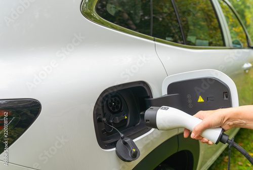 Close-up of a hand connecting a charger to an electric vehicle port