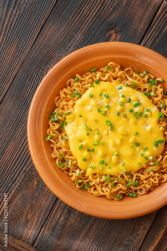 Cheesy corn ramen with scallions and wooden chopsticks on dark rustic table