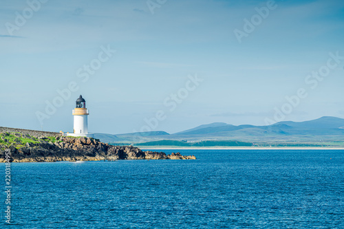 Phare de Lochindaal au bout de son promontoire, vu depuis la plage de Port Charlotte dans une lumière de fin de journée, île d'Islay, Ecosse
