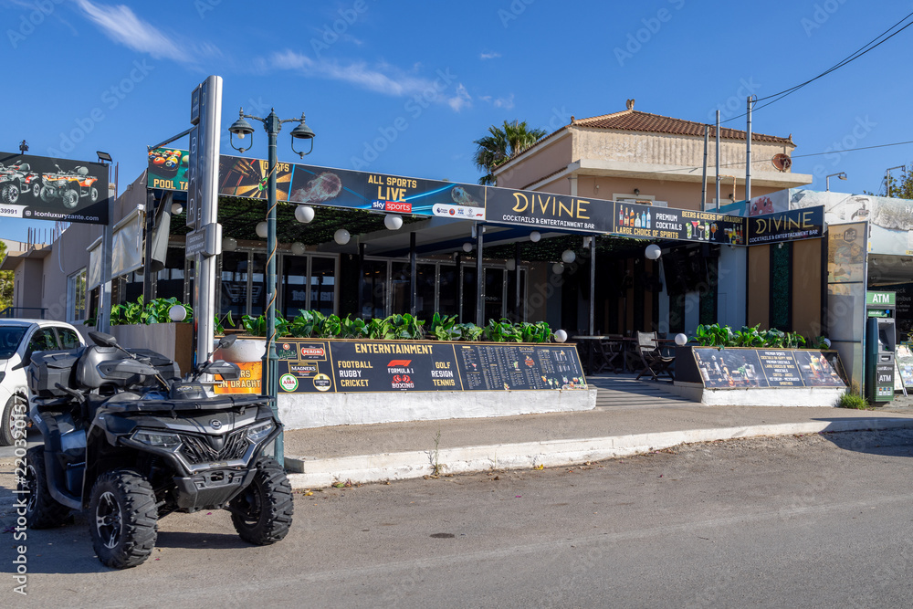 Obraz premium Kalamaki, Zakynthos Greece, 1st September 2026: Divine Cocktails and Entertainment Bar frontage with sports advertising outdoor seating menu boards plants and a quad bike outside