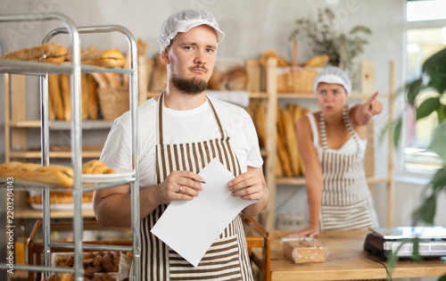 Foto In bakery, frustrated male employee during quarrel with girl boss