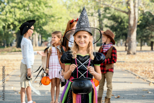 Little girl dressed for Halloween with her friends in park