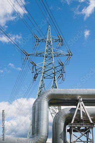 a pipeline and a power transmission tower against a blue sky