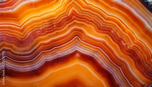 a macro image of an orange agate stone slice exhibits organic wavy patterns the polished crystalline sections display a translucent texture and natural banding the shimmering gemstone mineral surfac