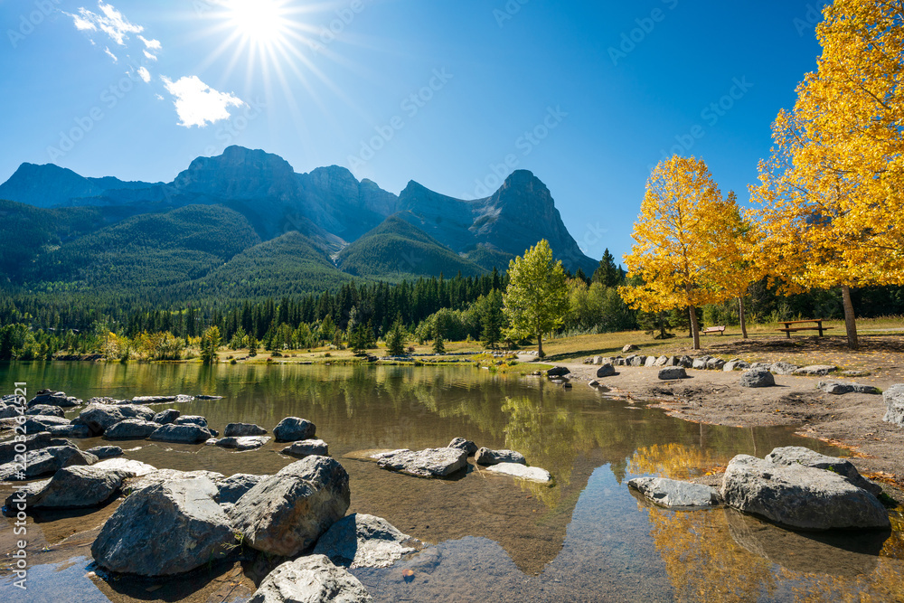 Fototapeta premium Quarry Lake autumn landscape with yellow leaves reflecting on clear water. Canmore, Alberta, Canada.