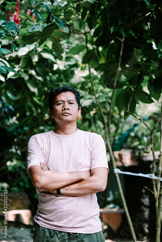Confident man with crossed arms standing in lush green garden