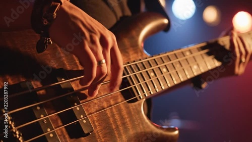 Close-up of a musician's hand playing bass guitar strings on stage during a performance
