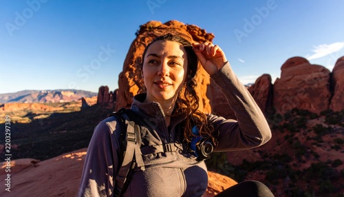 Young woman hiker posing on red rock mountains in Sedona during sunset