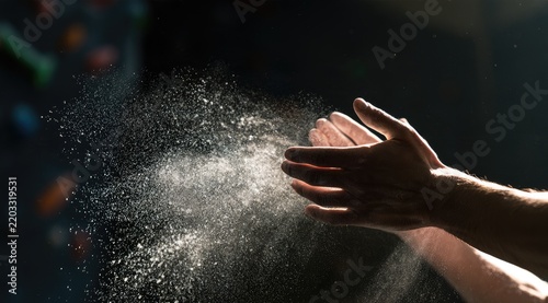 Hands clapping, releasing chalk dust in a dramatic ray of light