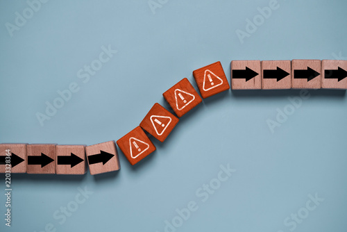 Risk management concept with warning symbols and directional arrows on wooden blocks represent business obstacles, crisis response, problem solving, uncertainty and strategic risk mitigation.