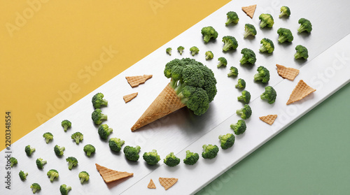 Creative Food Concept of Broccoli Vegetable in an Ice Cream Waffle Cone Surrounded by Florets and Waffle Pieces on Minimalist Background for Healthy Eating and Nutrition Lifestyle