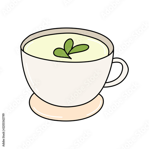 A delicious green matcha tea in a white ceramic cup with a green leaf garnish. The tea is served on a light peach saucer, creating a simple and elegant presentation