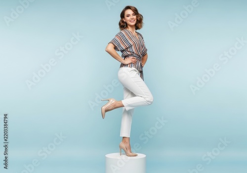 Woman posing with one leg raised on white block