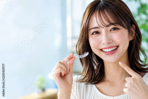 Plakat マウスピース矯正具を持って笑顔を見せる女性
