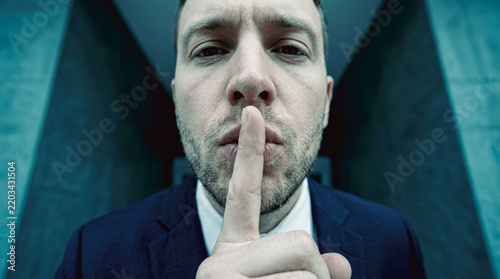 Businessman holding finger to lips in silence gesture