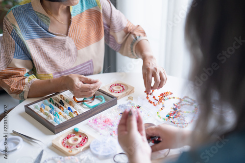Asian women teaching handmade beaded jewelry making in creative workshop for artisan business and community learning