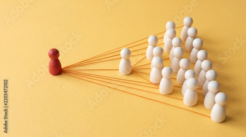 Red leader connected by strings directing organized group toward goals