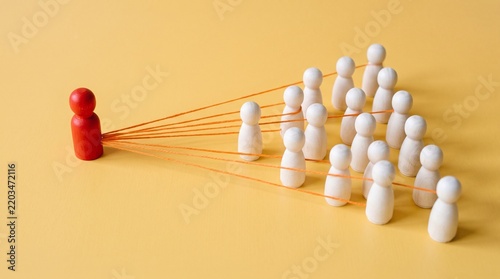 Red leader connected by strings directing organized group toward goals