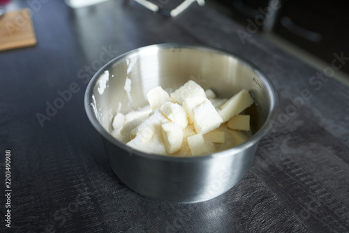 Cubes of butter and sugar in a metal bowl on a dark kitchen table. Cake preparation process.