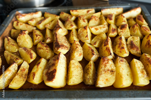 Fried potatoes on a baking sheet in the oven. Close-up.