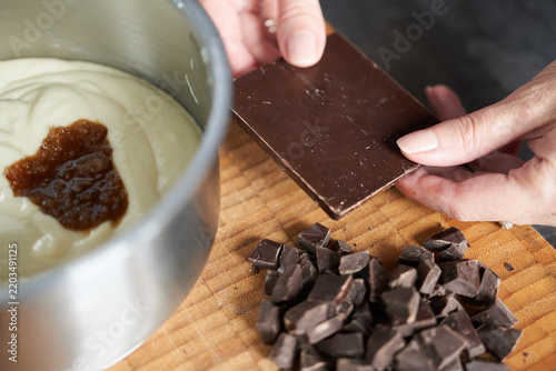 Close-up of a woman's hands putting chocolate in a metal bowl.